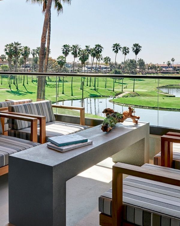 A patio features striped chairs around a stone table with a golf course view. Palm trees and water hazards are part of the scenic landscape.