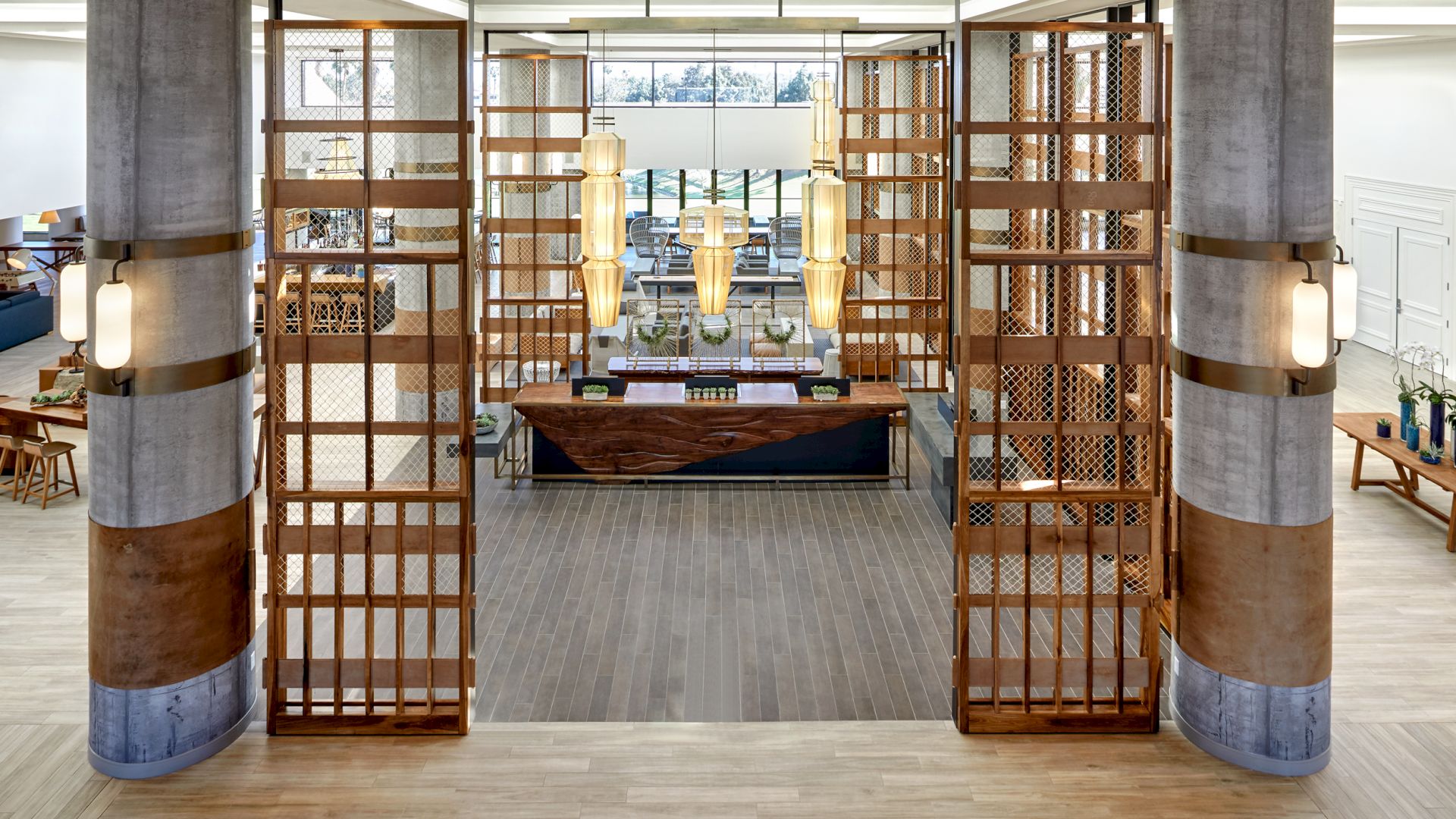 The image shows a spacious, modern lobby area with a wooden reception desk, contemporary light fixtures, and large, decorative wooden panels.