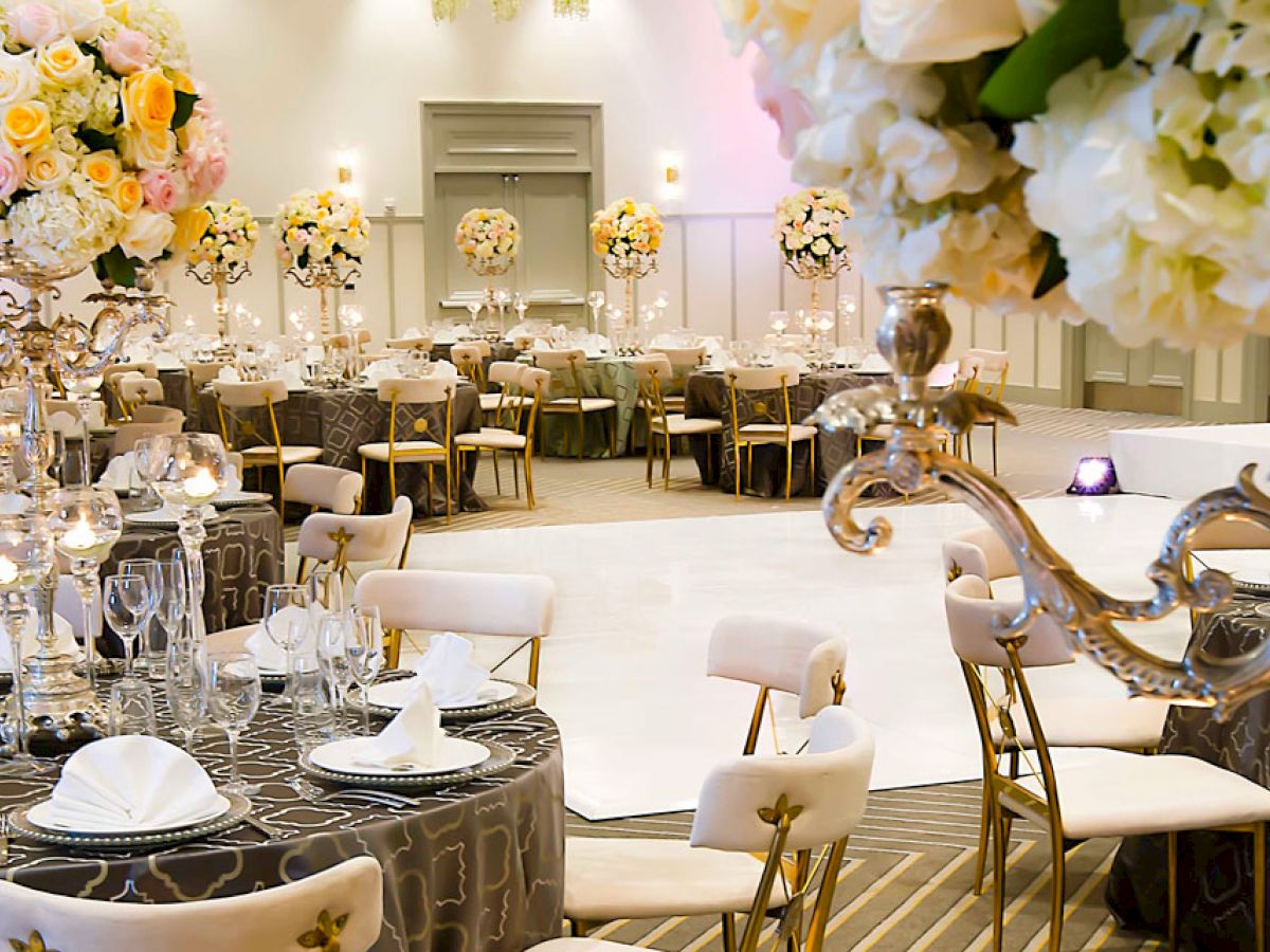 The image shows a beautifully decorated event hall with elegant table settings and floral centerpieces, likely for a wedding or formal event.