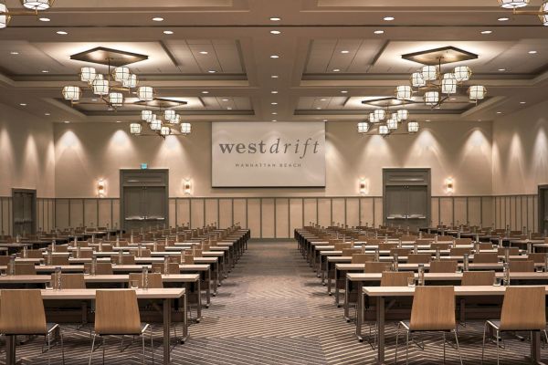 The image shows a conference room with rows of tables and chairs. The sign says 