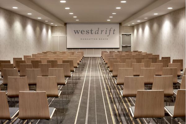 A modern conference room featuring rows of wooden chairs, a sign that reads 