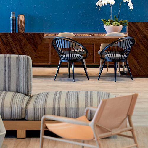 The image shows a modern, stylish room with a wooden table, chairs, a striped sofa, an armchair, and a wall with an ocean-themed decoration ending the sentence.