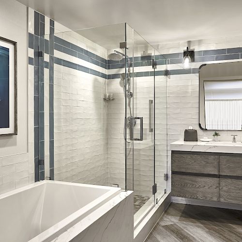 Modern bathroom with a bathtub, glass-enclosed shower, large mirror, vanity with sink and a wall picture showing a swimmer underwater, ending the sentence.