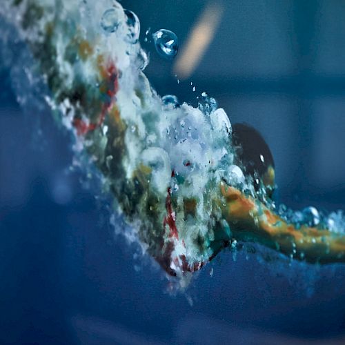 A swimmer captured mid-dive underwater with bubbles surrounding them, creating a dynamic and energetic scene.