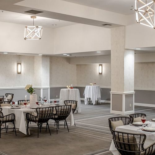 This image shows an elegantly decorated banquet hall with tables set for dining, featuring white tablecloths and arranged chairs.